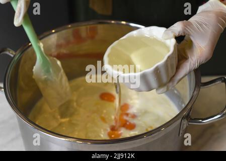 Hände in Gummihandschuhe rühren Teig für einen Kuchen Stockfoto