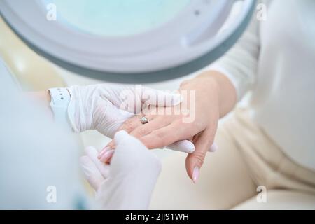 Doktor in weißen sterilen Handschuhen hält eine Frau Hand Stockfoto