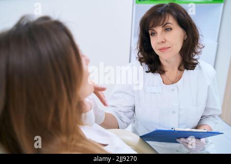 Dermatologe im Gespräch mit einem Patienten, der auf einem Stuhl sitzt Stockfoto