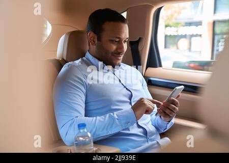 Zufrieden Passagier mit seinem Handy im Auto Stockfoto