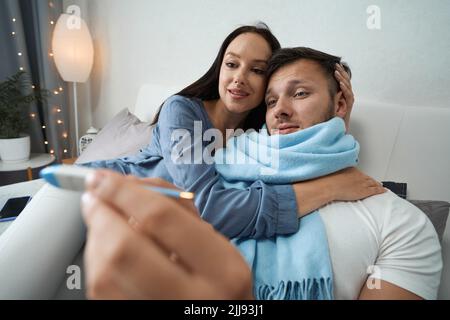 Mann mit leichter Unwohlsein im Bett in Begleitung seiner Freundin Stockfoto