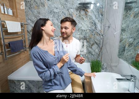 Der Typ und die Frau kommunizierten gerne im Badezimmer Stockfoto