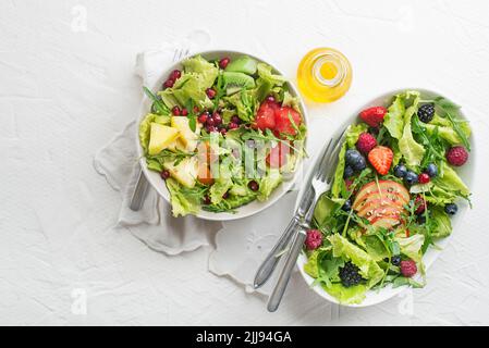 Frischer Salat mit Obst und Gemüse auf weißem Hintergrund, Draufsicht mit Platz für Text. Gesunde Ernährung. Stockfoto