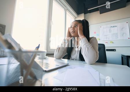Müder Mitarbeiter des Unternehmens, der am Arbeitsplatz Migräneanfälle erlebt Stockfoto