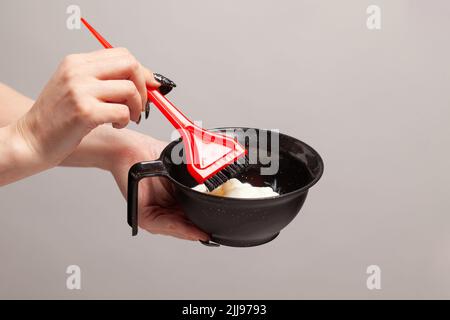 Hand von professionellen Friseur Mischen von Haarfarbe in einer Schüssel. Peroxid und rote Bürste, Nahaufnahme. Stockfoto