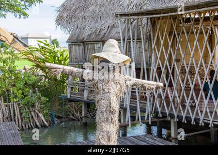 Ayutthaya Thailand 6. Jun 2022: Die Vogelscheuche mit schwarzer Maske wegen COVID-Einschränkung und Sicht auf Rak Na Ayutthaya im Reisfeld. Stockfoto