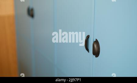 Blaue Schiebegarderobe mit stilvollen, zuverlässigen schwarzen Griffen zum Öffnen und Schließen Stockfoto