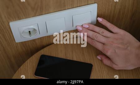 Frau drückt die Hand auf das Ausschalten der Lichter in Nahaufnahme Stockfoto