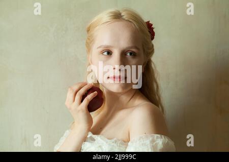 Porträt einer niedlichen blonden Frau mit rotem Apfel Stockfoto