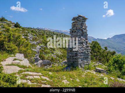 Stein-Obelisk-Steinwurf an einem Bergpfad oberhalb des Dorfes Tsepelovo in der Zagori-Region Nordgriechenlands mit dem Berg Timfi in der Ferne Stockfoto