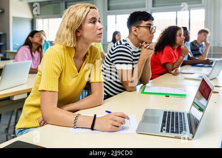 Gruppe von multiethnischen Studenten hören Lehrer im Klassenzimmer an der High School Stockfoto