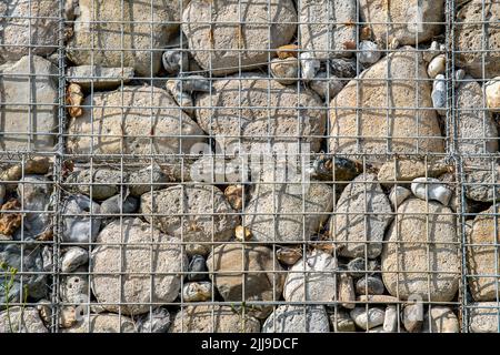 Nahaufnahme der Gabionenwand. Metallgitter mit Felsen für den Schutz des Meeres. Stockfoto