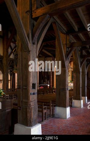 Massive quadratische Eichensäulen, die das Schiff und das Dach der Eglise Saint-Nicolas aus dem 16. Und 17. Jahrhundert in Outines in der Gegend Pays du der Marne in Grand Est, Frankreich, stützen, werden durch Verschrauben von Baumstämmen geformt. Das Gebäude ist das größte und monumentalste aller historischen Fachwerkkirchen oder Holzrahmenkirchen in der Champagne-Region. Stockfoto