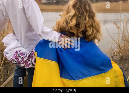 Junge und Frau gekleidet in traditionelle bestickte Kleidung mit blauer gelber Flagge. Hand des Kindes auf der Schulter des Erwachsenen. Konzept der Nation, Patriotismus, sup Stockfoto