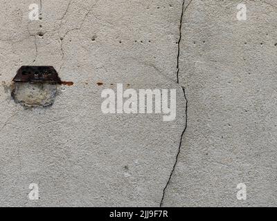 Perfekte Hintergrundaufnahme für Designer einer wunderschönen, einzigartigen beige-grau-weißen Wand mit einer Schlossdekoration auf der linken Seite und einem tiefen Riss in der Wand Stockfoto