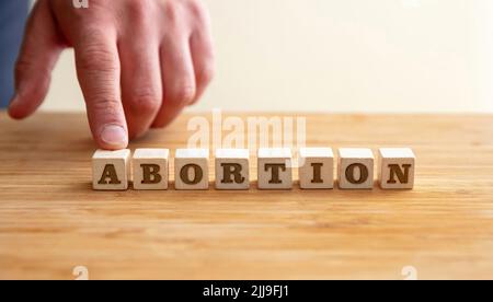 Abtreibung, Schwangerschaftsabbruch Konzept. Männliche Hand und Abtreibung Text auf Holzblöcken, Kopierraum. Stockfoto