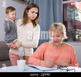 Erwachsene Frauen mit ihrer Mutter haben Unstimmigkeiten wegen Problemen beim Ausfüllen von Dokumenten Stockfoto