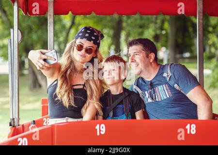 Coole und hippe moderne Familie, die ein Selfie in einem Open-Air-Bus während der Tour Ride Abenteuer Stockfoto