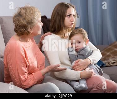 Zwei Erwachsene Frauen haben Meinungsverschiedenheiten mit dem erwachenden Kind Stockfoto