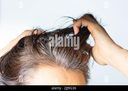 Kopf der kaukasischen Frau mittleren Alters mit schwarz grauen Haarwurzeln. Nahaufnahme Stockfoto