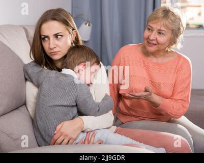 Zwei Erwachsene Frauen haben Meinungsverschiedenheiten mit dem erwachenden Kind Stockfoto