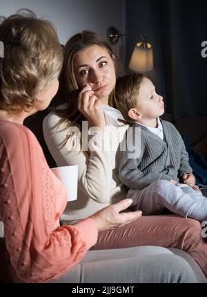 Die Erwachsene Frau weint, nachdem sie einen Film gesehen hat, und ihre Mutter tröstet sie am Abend Stockfoto