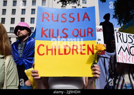 London, England, Großbritannien. 24.. Juli 2022. Ein Protestler hält vor der Downing Street ein Plakat mit der Aufschrift „„Russland tötet unsere Kinder““. Hunderte von Menschen marschierten aus Solidarität mit der Ukraine von Marble Arch zur Downing Street, während der Krieg mit Russland weitergeht. (Bild: © Vuk Valcic/ZUMA Press Wire) Stockfoto