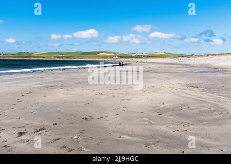 dh Skaill Bay SANDWICK ORKNEY Paar zu Fuß entlang Sandstrand blaues Meer Sommer Himmel Sand Stockfoto