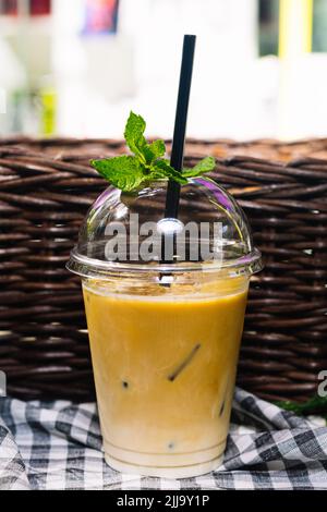 Eiskaffee in einer durchsichtigen Plastikbecher mit einem Strohhalm. Es ist ein heißer Sommer. Ein erfrischendes Getränk. Verziert mit Minzblättern. Stockfoto