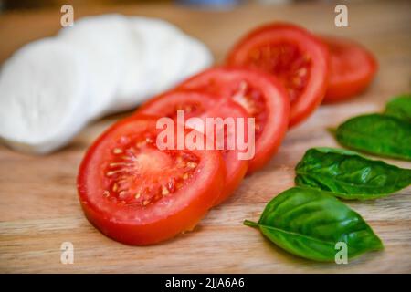Tomaten auf der Rebe - Solanum lycopersicum - Basilikum-Mozzarella-Salat mit roten Tomaten - Mozarella - vegetarische Lebensweise und Kochkost - reife Tomaten Stockfoto