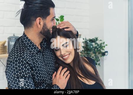 Vertrauen und Glück in einer Beziehung. Heterosexuelles Paar von zwei attraktiven Menschen kuscheln in der Küche. Nahaufnahme mittlere Aufnahme. Hochwertige Fotos Stockfoto