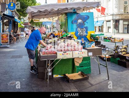 Obststand vor der U-Bahnstation Goodge Street, Tottenham Court Road, Central London, mit Covid Germ Graffiti an der Seite. Stockfoto