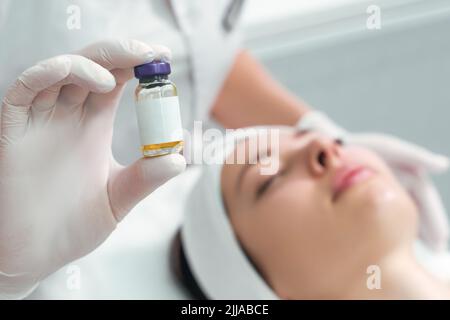 Eine Frau hält ein kosmetisches Produkt in der Hand. Injektionslösung. Stockfoto