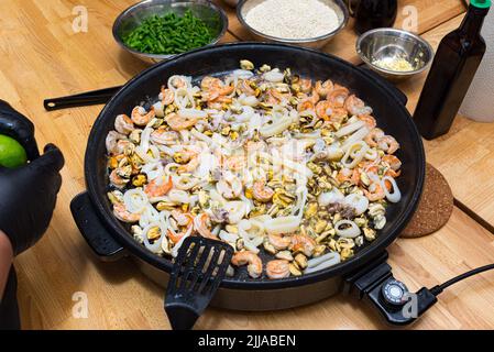 Meeresfrüchte in einer Paella-Schale (Paella-Pfanne) gebraten. Meeresfrüchte-Cocktail. Garnelen, Tintenfische, Kraken, Muscheln. Stockfoto