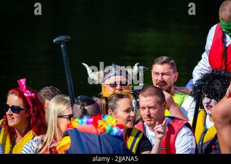 Mann im Wikinger-Outfit mit gehörntem Hut, der bei einem Drachenboot-Rennen unter Kollegen sitzt Stockfoto