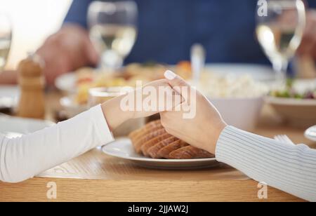 Vielen Dank, dass Sie an meiner Seite sind. Zwei unkenntliche Menschen halten sich zu Hause am Esstisch die Hände. Stockfoto