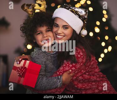 HES das beste Geschenk, das ich je erhalten habe. Eine junge Mutter und ein Sohn tauschen Weihnachtsgeschenke zu Hause aus. Stockfoto