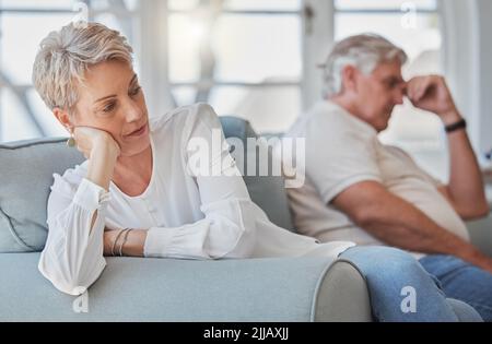 Sie hasst es zu kämpfen. Ein älteres Paar, das nach einem Streit traurig und aufgeregt in ihrem Wohnzimmer sitzt. Stockfoto