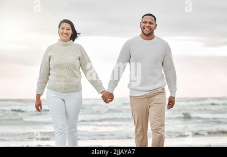 Hand in Hand. Ein liebevolles junges Paar, das einen intimen Moment am Strand teilt. Stockfoto