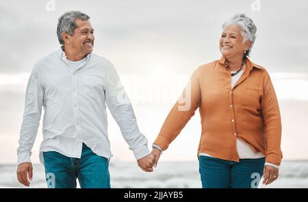 Romantik stirbt nie. Ein liebevolles Seniorenpaar, das einen intimen Moment am Strand teilt. Stockfoto