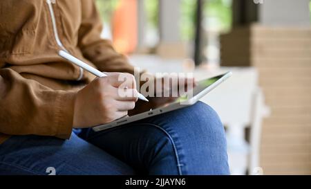 Hipster weibliche freiberufliche Grafikdesignerin Fernarbeit im Café, mit digitalem Tablet, um ihr Kunstwerk zu skizzieren. Zugeschnittenes Bild Stockfoto