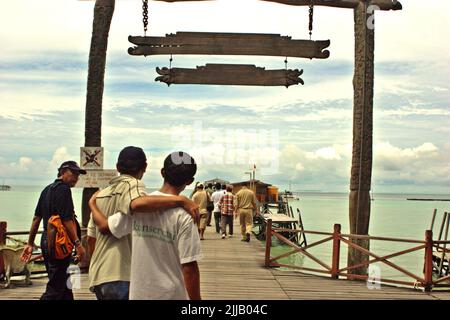 Menschen, die auf einem Steg auf der Insel Derawan, einem Teil des Berau Marine Protected Area innerhalb der Derawan Inseln in Berau, Ost-Kalimantan, Indonesien, wandern. Stockfoto