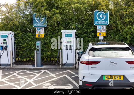 Der elektrische Jaguar i-Pace in Weiß wird an einer Autobahndienststelle in England über das Gridserve-Ladestationsnetz aufgeladen. England, Großbritannien Stockfoto