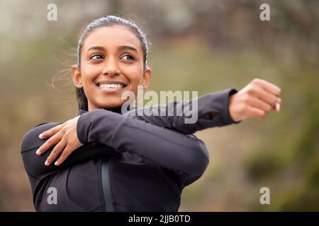 Mach dich bereit, den Brand zu spüren. Eine junge Frau, die sich vor dem Joggen ausdehnt. Stockfoto