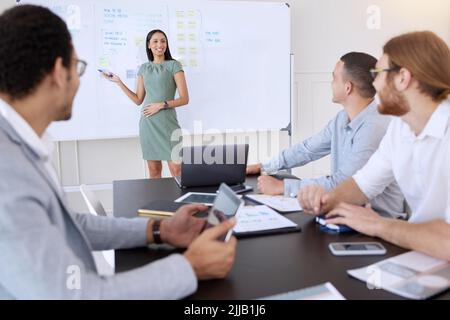 Ich bin zuversichtlich, dass dieser Plan funktionieren wird. Eine junge, Schwangere Geschäftsfrau steht und gibt während eines Treffens im Büro eine Präsentation. Stockfoto