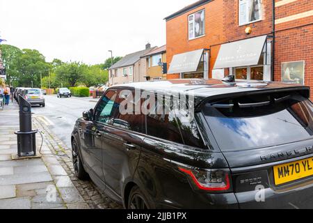 Der schwarze Range Rover Sport Hybrid wird mit dem Straßen-EV-Ladegerät in Whalley, in der Nähe von Clitheroe, Lancashire, Großbritannien, aufgeladen Stockfoto