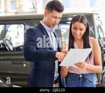 Ich denke, das ist sehr viel. Ein Autoverkäufer und ein Kunde, der sich Papierkram ansieht. Stockfoto