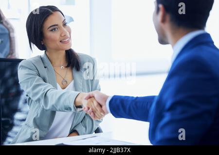 Eine attraktive junge Frau und ein unkenntlich männlicher Autoverkäufer, der sich in seinem Büro die Hände schüttelt. Stockfoto