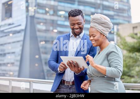 Die Technologie bringt uns zusammen: Zwei Kollegen nutzen ein digitales Tablet vor dem Hintergrund der Stadt. Stockfoto