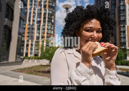 Multirassische Frauen beißen sich ein Sandwich auf Weißbrot Stockfoto